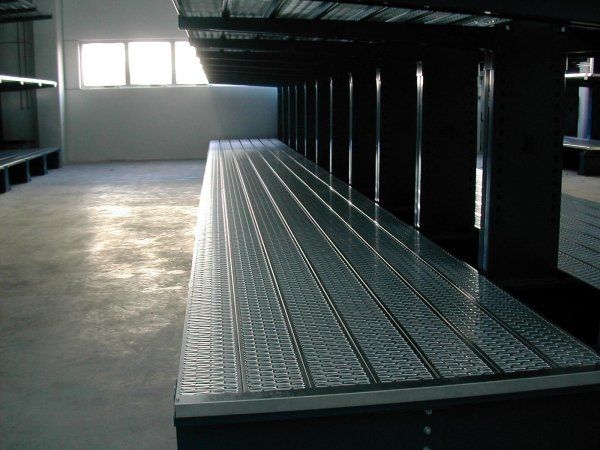 Scaffalatura industriale in metallo all'interno di un magazzino, con una finestra luminosa sullo sfondo.