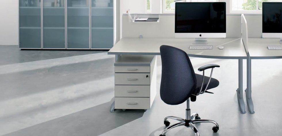 Una moderna postazione di lavoro in ufficio con scrivania grigia, sedia ergonomica blu scuro e monitor.