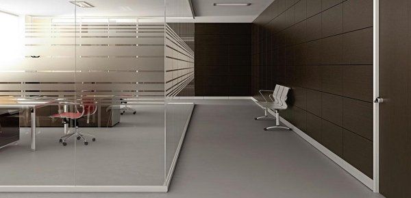 Un corridoio d'ufficio moderno con pareti divisorie in vetro, una parete rivestita in legno scuro e posti a sedere nella zona d'attesa.