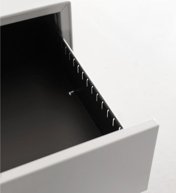 Un cassetto aperto in metallo grigio chiaro con fessure laterali nere per appendere le cartelle.