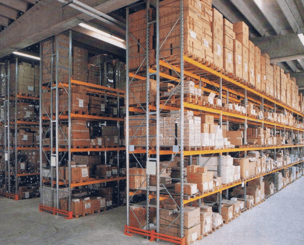 In un magazzino, si può ammirare un'alta scaffalatura industriale metallica a più livelli, piena di numerose scatole di cartone.