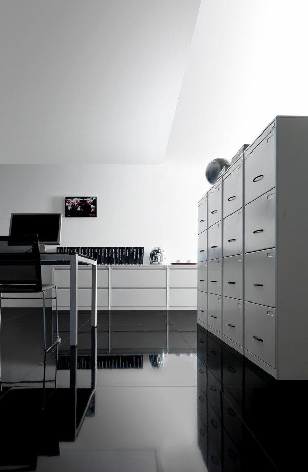 Un ufficio elegante e moderno, caratterizzato da una scrivania nera, schedari e un pavimento scuro lucido che riflette la luminosità dell'ambiente.