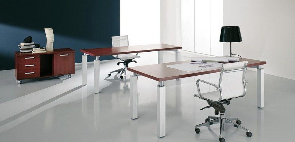 Due scrivanie moderne con gambe bianche e piani color legno, abbinate a sedie da ufficio bianche, in una stanza luminosa e minimalista.