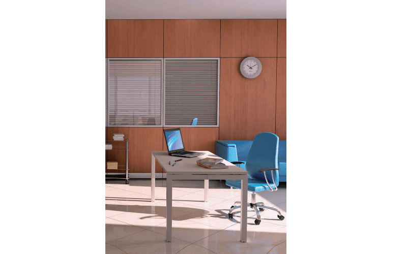 Una scrivania con un computer portatile e una sedia da ufficio blu in una stanza luminosa e moderna con pareti rivestite in legno e un orologio a parete.