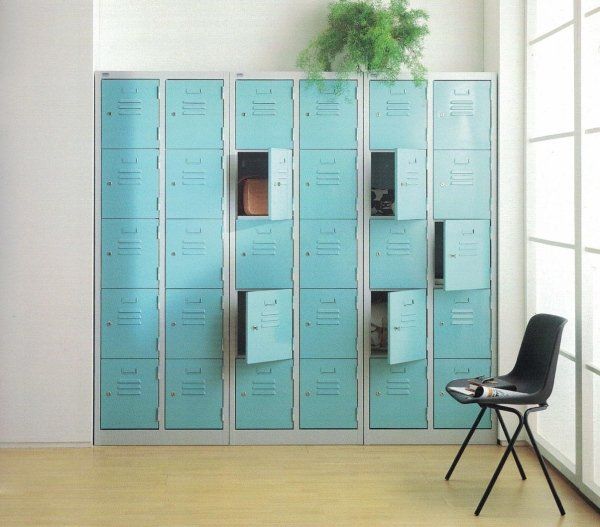 Una parete di armadietti azzurri, alcuni aperti, accanto a una moderna sedia nera in una stanza luminosa e minimalista.