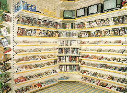 Gli scaffali del negozio erano pieni di numerose videocassette VHS e DVD, con diversi piccoli televisori vintage allineati in cima.