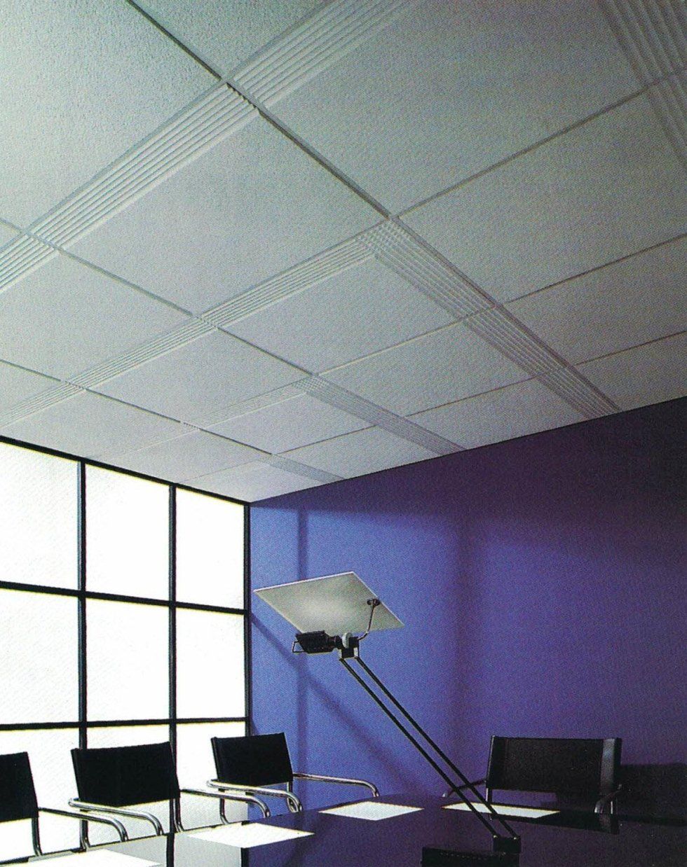 Una sala riunioni con controsoffitto, una moderna lampada da scrivania, sedie nere e una finestra su una parete viola scuro.