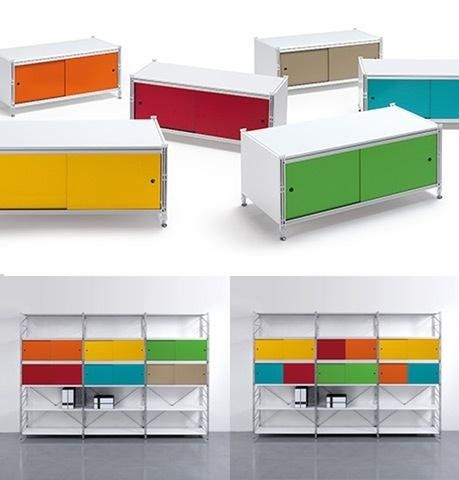 Una collezione di mobili contenitori e scaffalature modulari bianchi con ante colorate, in un ambiente monolocale.