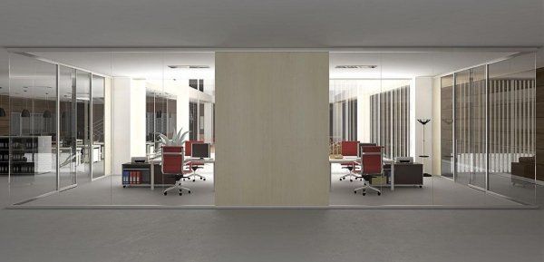 Interno di un ufficio moderno con due aree di lavoro simmetriche racchiuse da pareti in vetro, dotate di scrivanie e sedie rosse che fiancheggiano una parete.