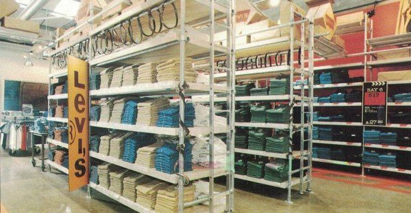 In un negozio, sugli scaffali sono esposte pile di jeans Levi's piegati e ordinati per colore e modello.