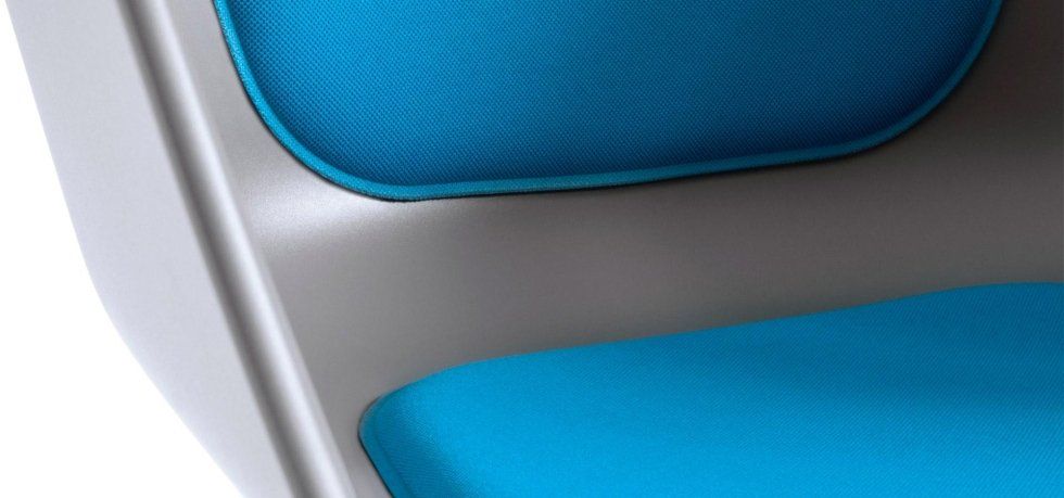 Primo piano di una moderna sedia dalla struttura curva di colore grigio, con seduta e schienale imbottiti di un blu brillante.