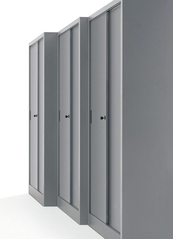 Una fila di tre armadietti identici, alti e moderni, di colore grigio, con pomelli circolari neri, su uno sfondo bianco uniforme.