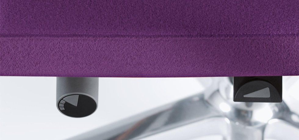 Primo piano di due manopole di regolazione poste nella parte inferiore del sedile di una sedia da ufficio viola.
