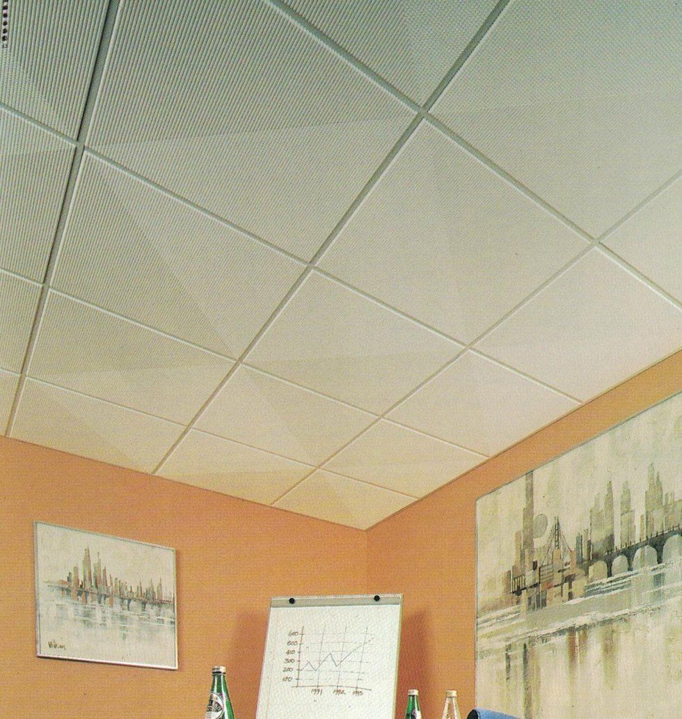 Una stanza con pareti arancioni decorate con opere d'arte e una lavagna bianca sotto un controsoffitto bianco.