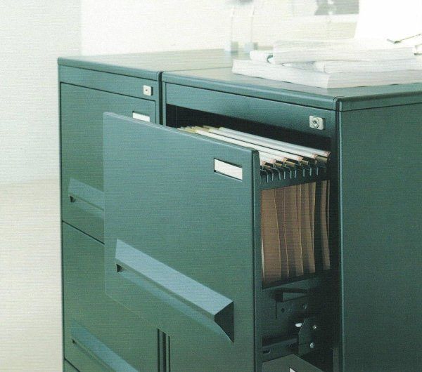 Un classificatore in metallo verde scuro con un cassetto parzialmente aperto, che lascia intravedere all'interno delle cartelle sospese.