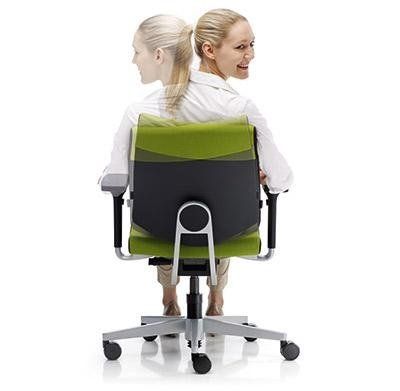 Due persone siedono schiena contro schiena su un'unica sedia da ufficio moderna con schienale verde e nero su sfondo bianco.