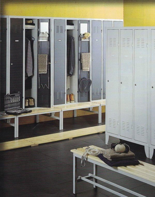 Armadietti grigio chiaro con ante aperte contenenti abiti e accessori, situati in uno spogliatoio con panche in legno.