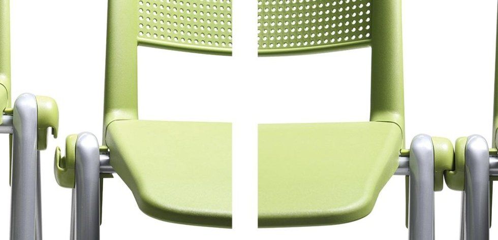 Una fila di sedie in plastica verde e metallo argentato con schienale a griglia su sfondo bianco.