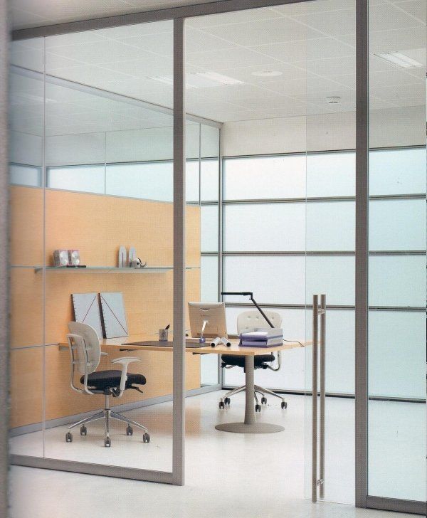 Interni di ufficio moderni con due postazioni di lavoro separate da una parete divisoria in vetro, caratterizzate da scrivanie in legno e sedie ergonomiche.
