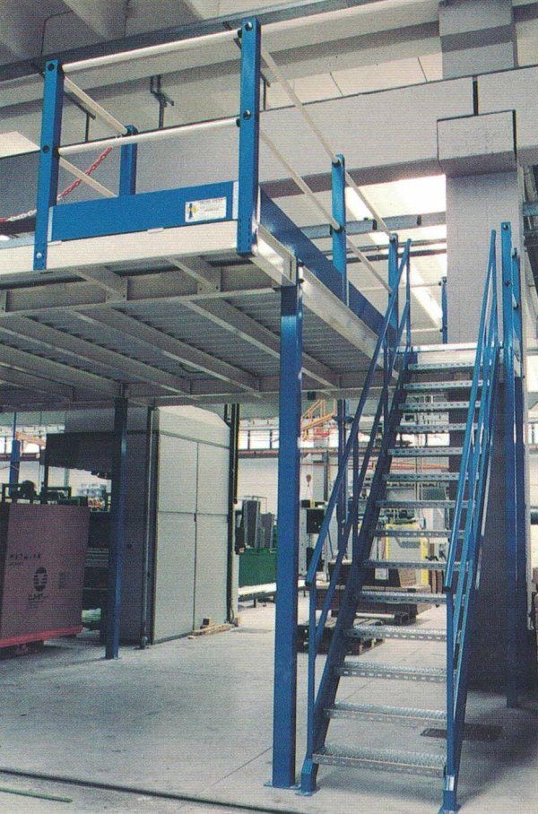 Soppalco blu con scale e parapetti di sicurezza in un ambiente di magazzino.