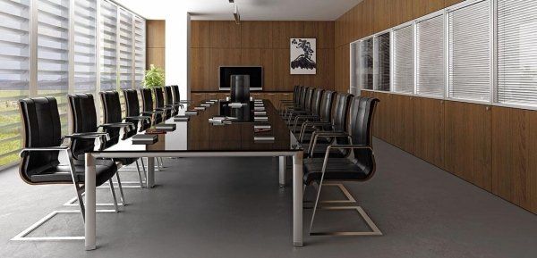 Una moderna sala riunioni con un lungo tavolo scuro circondato da sedie nere, sullo sfondo di pareti rivestite in legno e vetrate a tutta altezza.