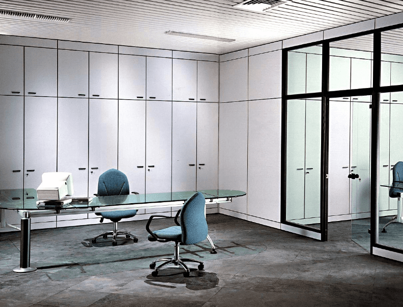 Un ufficio moderno con scrivania in vetro, due sedie da ufficio blu e armadi a muro bianchi a tutta altezza.