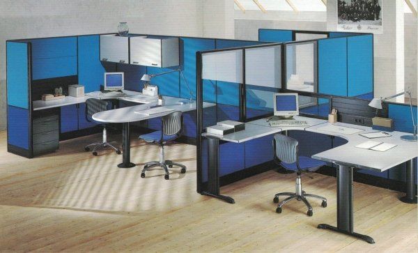 Un ufficio open space con postazioni modulari, scrivanie, sedie e pensili di colore blu e grigio.