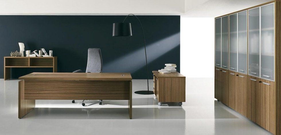 Moderno ufficio direzionale con scrivania in legno, credenza e armadietti coordinati, sedia grigia e lampada da terra.