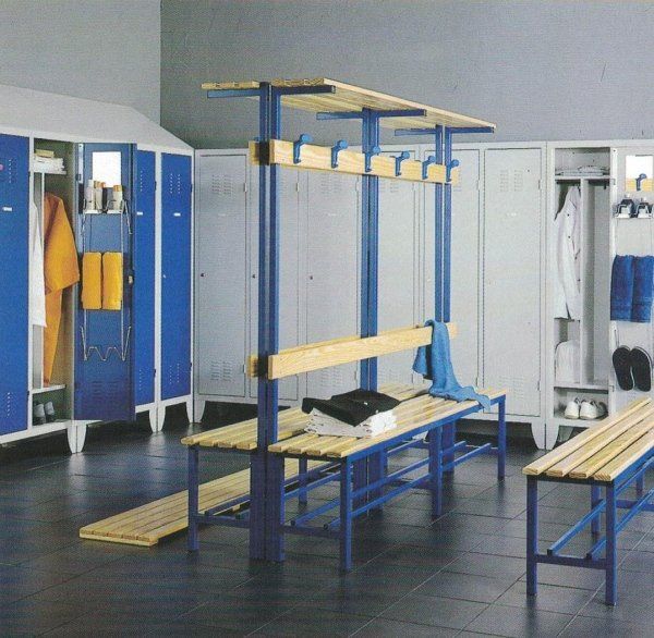 Uno spogliatoio con file di armadietti blu e bianchi e una panca centrale in legno con appendiabiti e ripiano.
