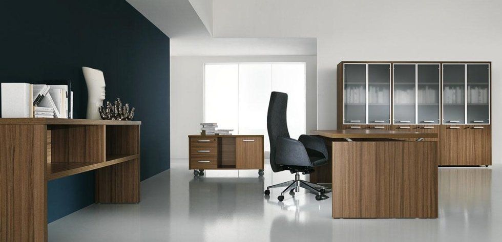 Ufficio moderno con mobili con finitura noce, una parete d'accento scura e una sedia ergonomica nera su un pavimento bianco riflettente.