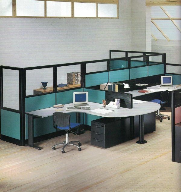 Un moderno spazio di lavoro in ufficio con scrivanie curve, divisori color verde acqua, cornici nere e sedie con rotelle su un pavimento in legno chiaro.