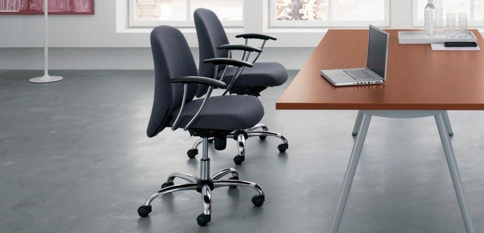 In una stanza luminosa e moderna, due sedie da ufficio grigie con rotelle sono posizionate accanto a una scrivania marrone con un computer portatile.