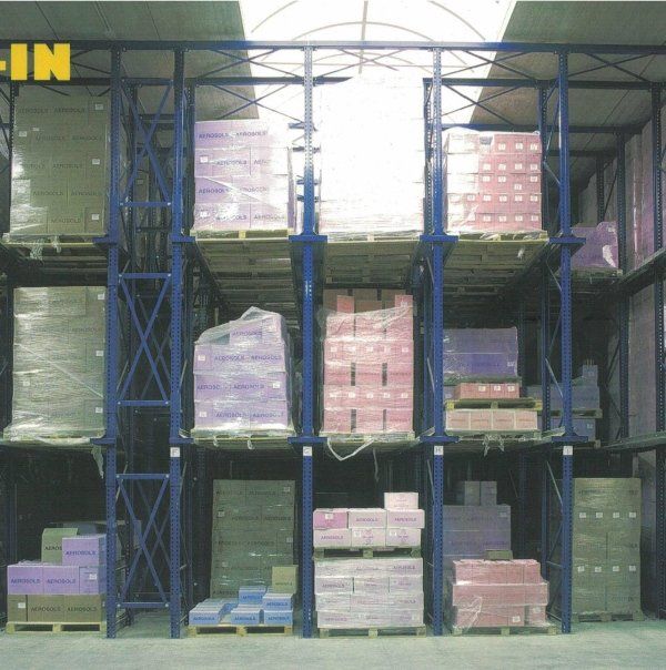 Sistema di scaffalature drive-in per magazzino, riempito con diverse merci stoccate su pallet all'interno di una struttura in acciaio.