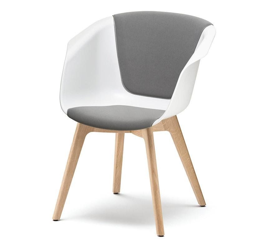 Una sedia moderna con seduta a secchiello sagomata bianca, cuscini in tessuto grigio e gambe in legno chiaro.