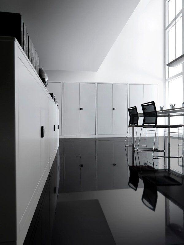 Un interno minimalista con mobili bianchi, un pavimento nero lucido che riflette la stanza e sedie moderne accanto a una grande finestra.