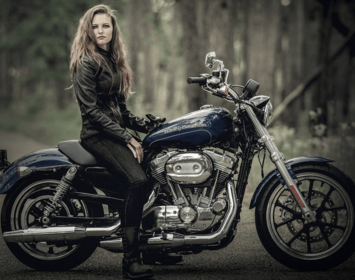 A woman is sitting on a blue harley davidson motorcycle.