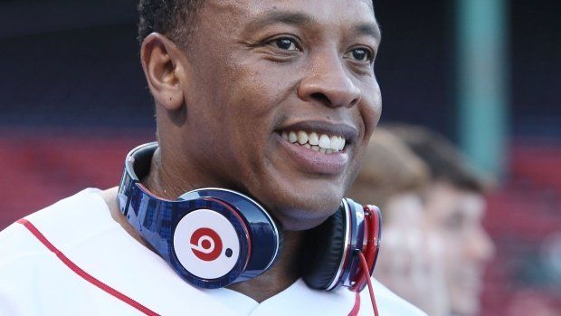 A man wearing headphones and a white shirt is smiling