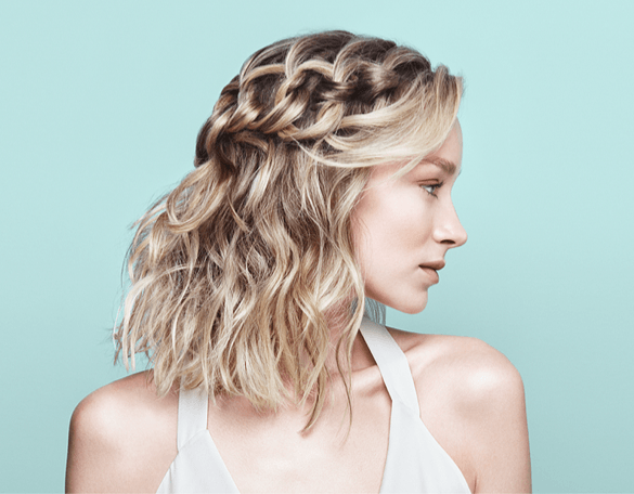 A woman with a braid in her hair is wearing a white tank top.