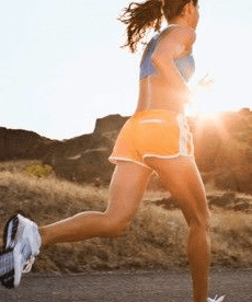 A woman in shorts is running down a road.