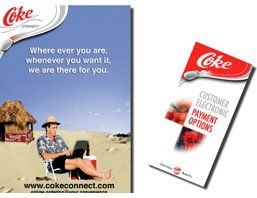 An advertisement for coke shows a man sitting on the beach with a laptop