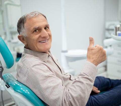 Senior Man Sitting on a Dental Chair — Grand Rapids, MI — Dentures In a Day A person who received full mouth dentures near Wyoming, MI