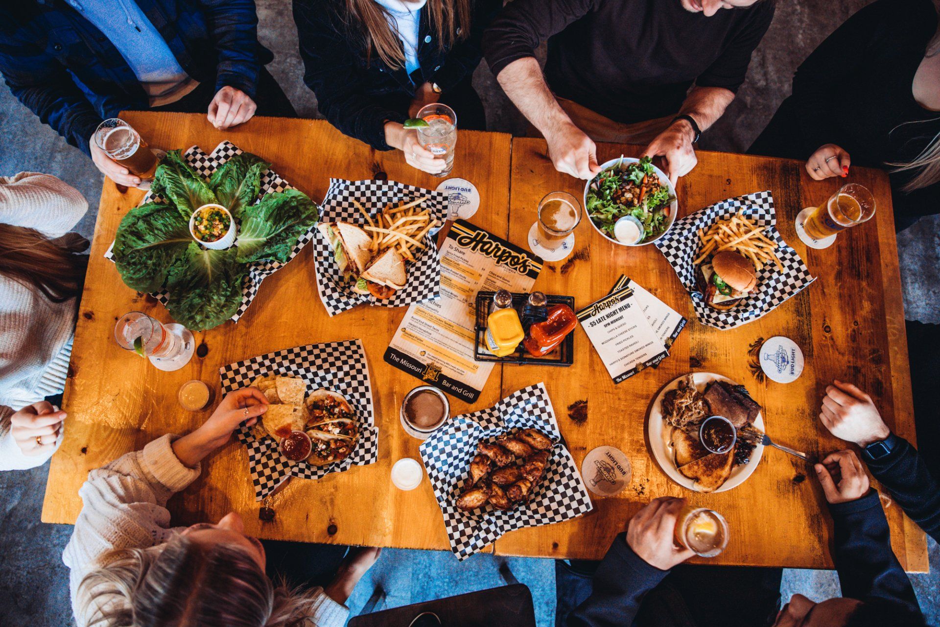 A group of people are sitting around a wooden table eating food.