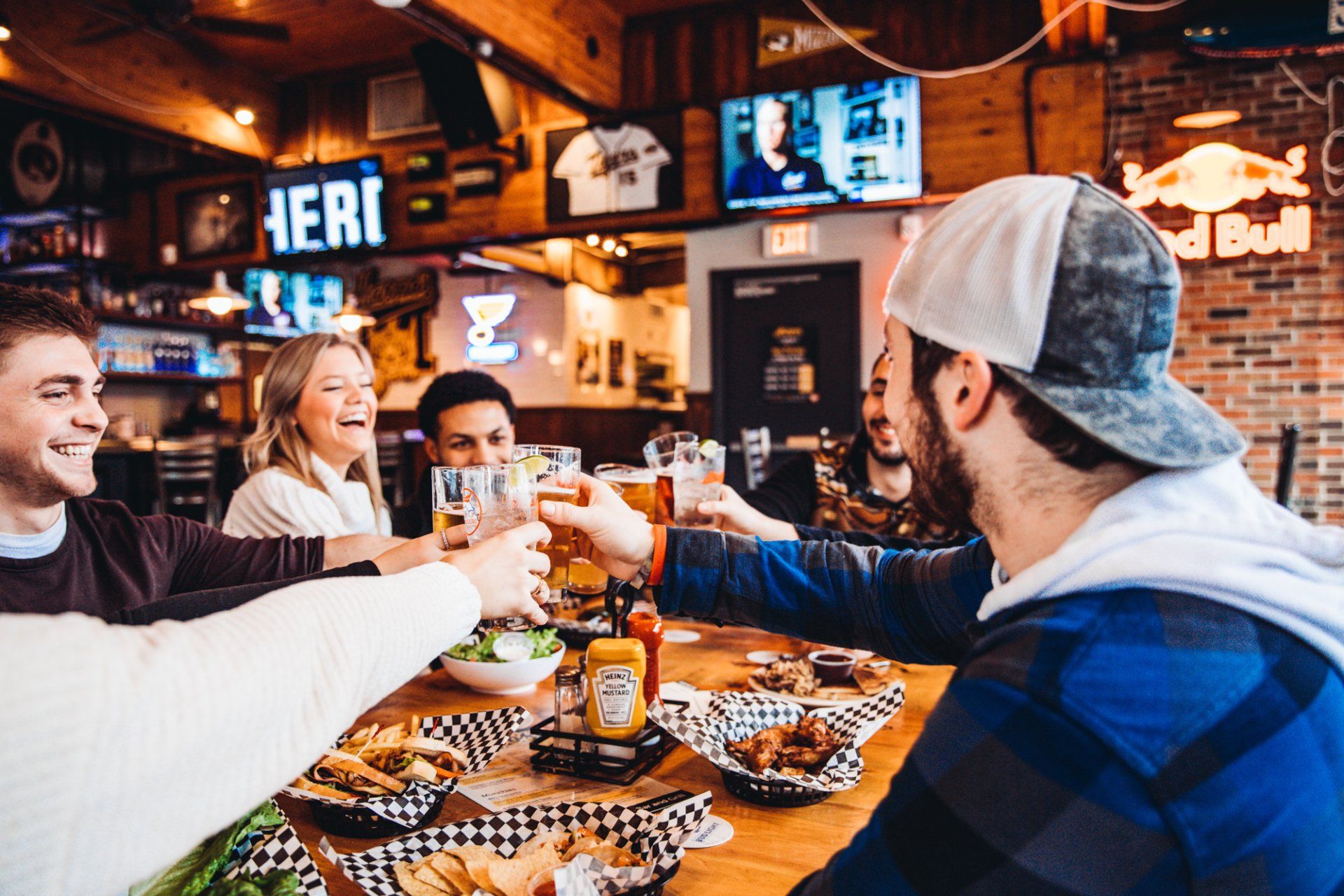 A group of people are sitting at a table in a restaurant toasting with beer.