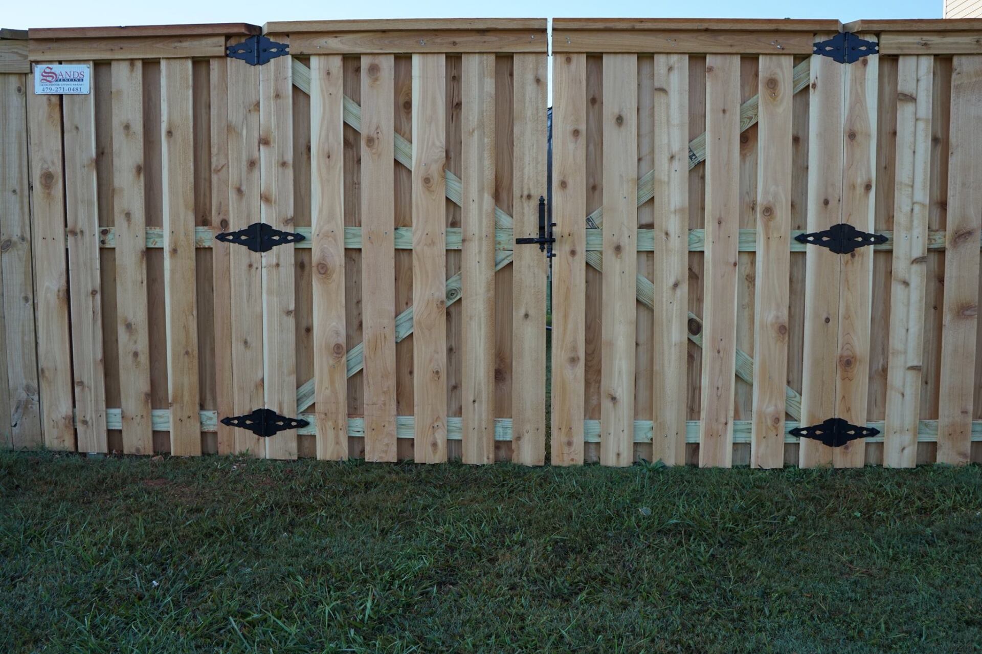 Wooden backyard fence with black hardware and grass at the bottom