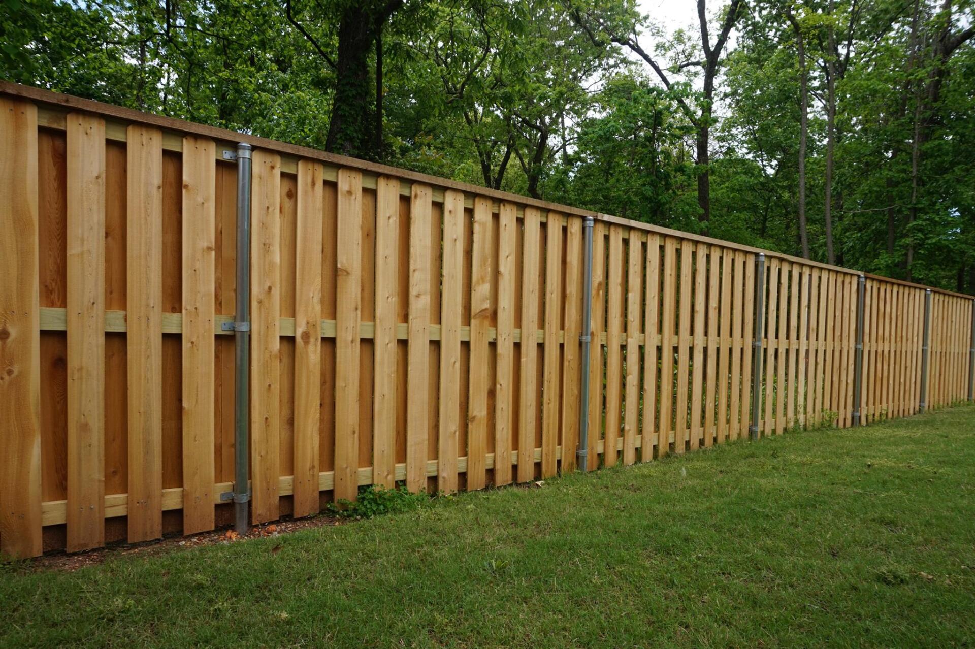 Long wooden privacy fence along a grassy yard beside trees