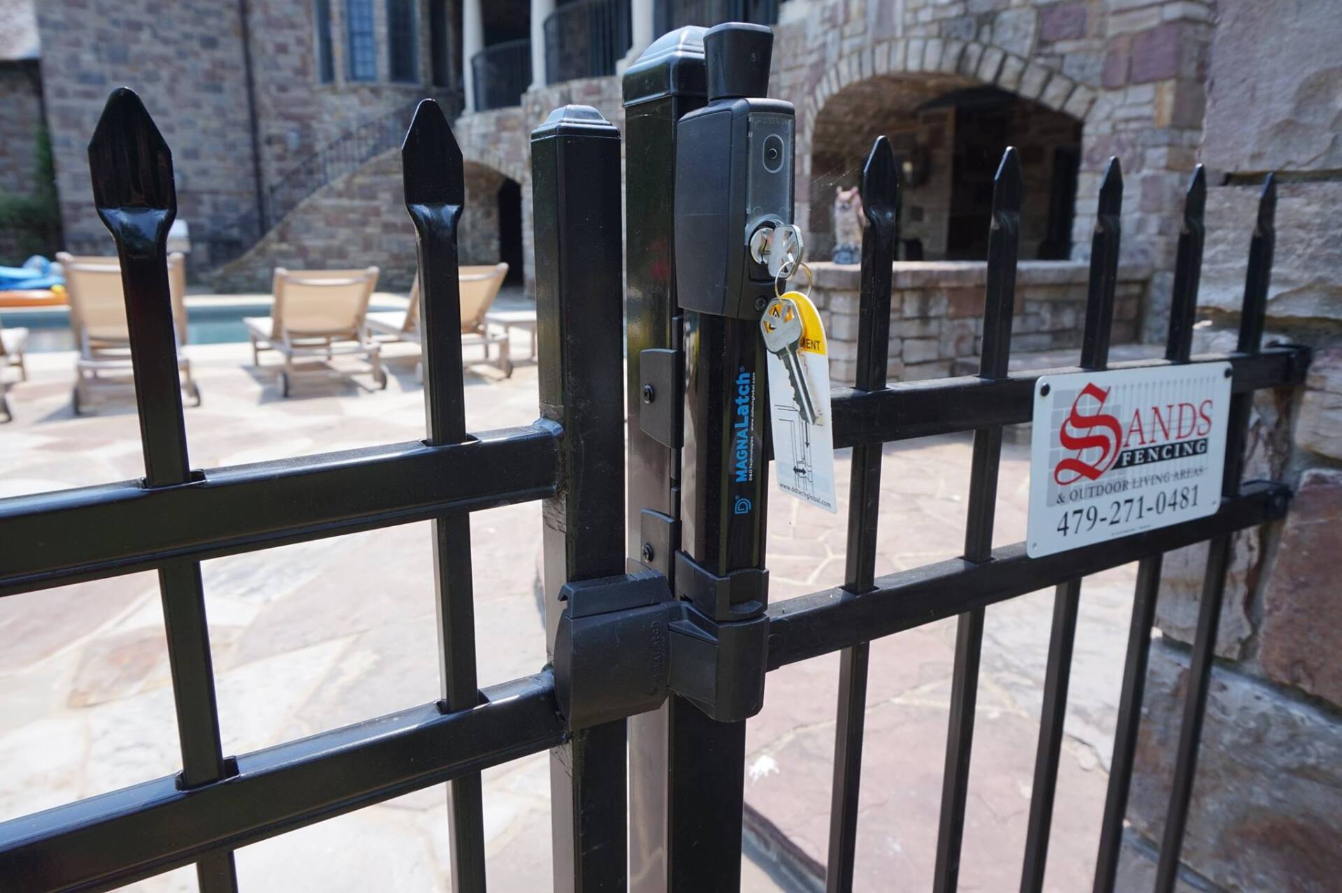 Black iron gate with keypad lock in front of a stone courtyard and arches
