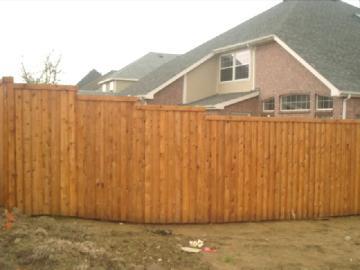 Wooden backyard fence in front of suburban houses under an overcast sky