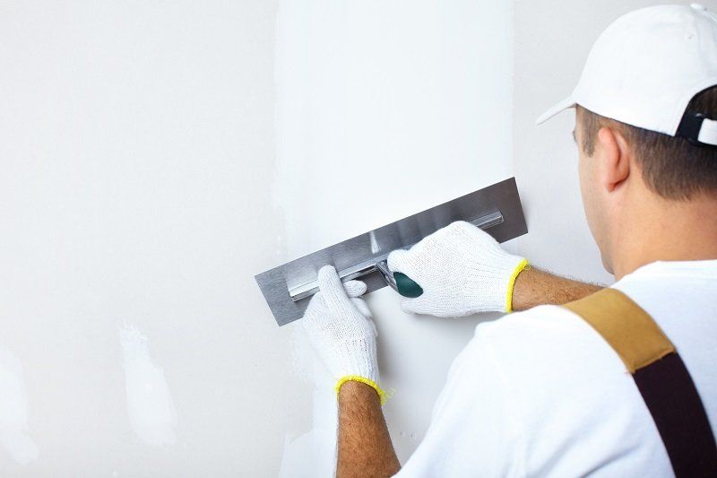 man in overalls skimming wall