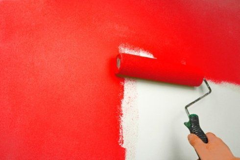 mano di una persona che imbianca un muro di rosso