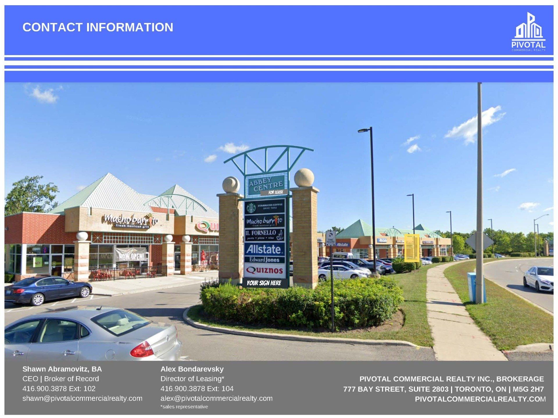 Exterior view of a commercial plaza with a central tenant directory sign and parking lot under a sunny blue sky.